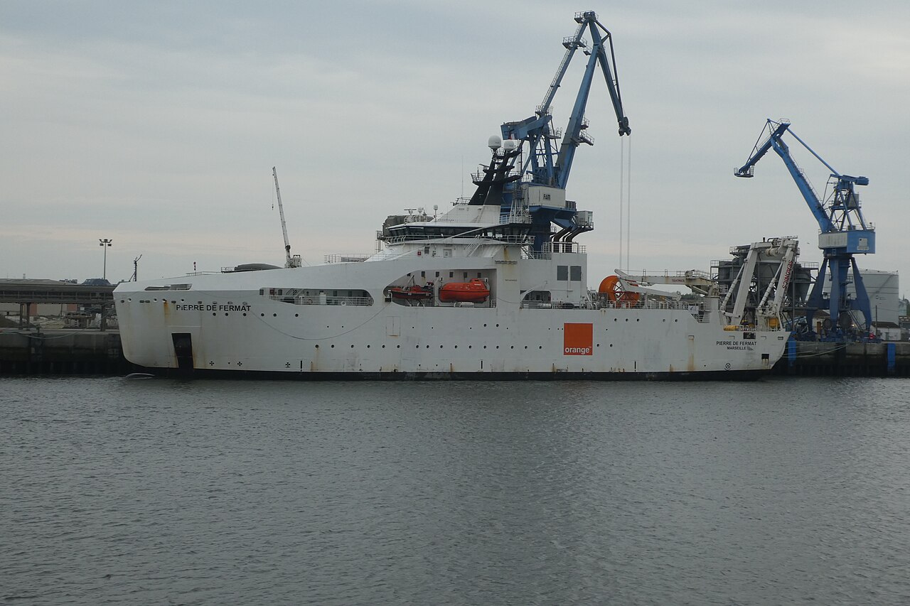 The cable ship Pierre de Fermat alongside a quay, showing its specialised hull and deck equipment. This is an illustrative photograph of a cable vessel, not a photograph of a particular incident, an active repair or an assigned vessel for any scenario in this article.